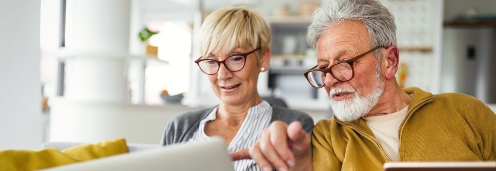Zwei ältere Personen nutzen gemeinsam einen Laptop.